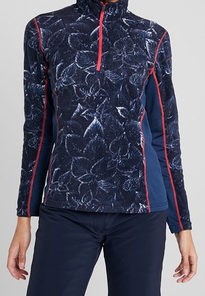 Donkerblauwe fleece trui met bloemenprint, voorzien van een rode rits en naadtoontjes, gedragen met donkermarineblauwe broek, toont het bovenlichaam en de armen.
