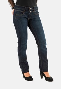 Jeans de mezclilla azul oscuro con un diseño ajustado, que presentan dos bolsillos delanteros y cierre de doble botón. Decorados con costuras doradas.
