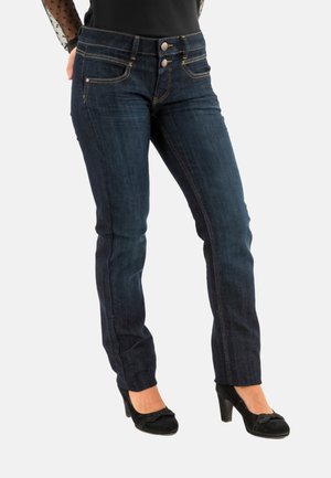 Jeans in denim blu scuro con design aderente, dotati di due tasche frontali e chiusura a doppio bottone. Accentuati da cuciture dorate.