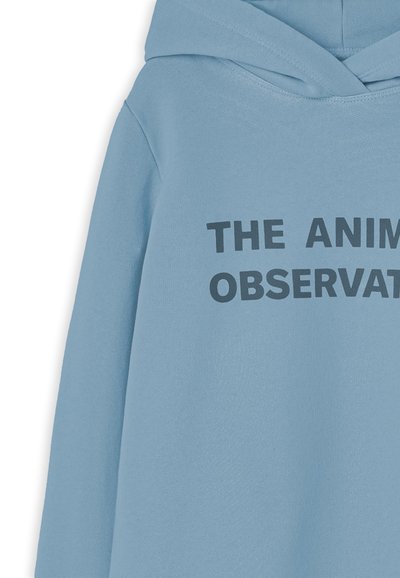 Sudadera de color azul claro hecha de algodón con un bolsillo frontal. Presenta el texto "LA OBSERVACIÓN DE ANIMALES" en letras negras y en negrita.