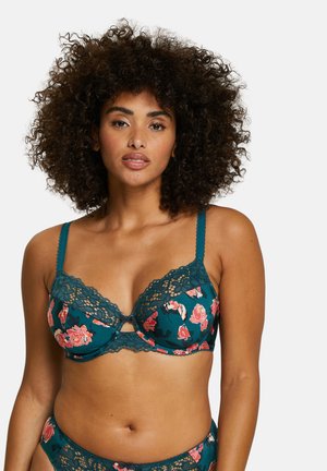 Reggiseno in pizzo color teal con stampa floreale rosa e bianca, design a chiave al centro e spalline regolabili. Tessuto morbido.
