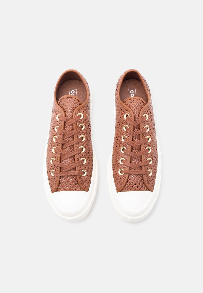 Brown woven lace-up sneakers with white rubber toe caps and soles, viewed from above on a light gray background.