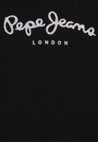 Musta kangas, jossa keskellä näkyy leikkisällä käsinkirjoitusfontilla hopeanhohtoinen kimaltava logo, jossa lukee "Pepe Jeans LONDON".