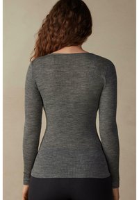 Šedý žebrovaný top s dlouhým rukávem a přiléhavým střihem, s výstřihem do tvaru lodičky a texturovanou tkaninou, z pohledu ze zadu.