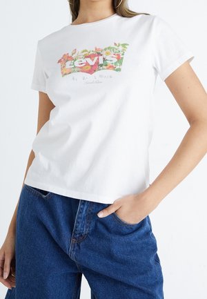 Biała bawełniana koszulka z kolorowym logo Levi's otoczonym kwiatowymi wzorami. Krótkie rękawy i luźny krój, zestawiona z niebieskimi dżinsami.