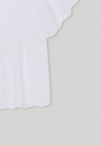 Top bianco a maniche corte con ricamo occhiello, orlo a scallop e un tessuto leggero e testurizzato che migliora la traspirabilità.