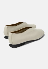 Spetsiga lägen skor i ljusbeige läder. Har en låg svart klack och en slät yta, med minimalt med sömmar och rena linjer.