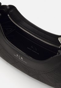 Borsa nera in tessuto con apertura con zip, caratterizzata da un interno liscio e un design con logo in rilievo. Presenta dettagli in hardware argentato.