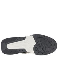 Černo-bílá podrážka tenisky s texturovanou gumou pro přilnavost, se výrazným kruhovým designovým prvkem uprostřed a vícesměrným vzorem.