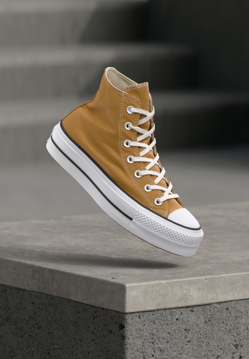 Sneaker alta in tela giallo senape con lacci bianchi, puntale in gomma e suola bianca strutturata con strisce nere.