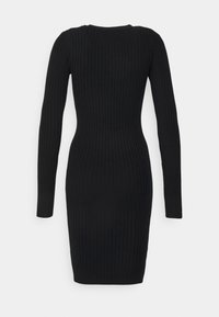 Robe en maille côtelée noire avec manches longues, silhouette ajustée, encolure ronde et longueur mi-cuisse. Aucun élément métallique visible ni motifs.