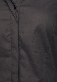 Czarna koszula na guziki wykonana z gładkiej tkaniny, z ukrytym listwą i ostrym kołnierzem, o jednolitej, gładkiej powierzchni.