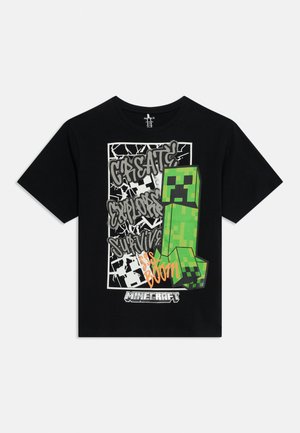 Maglietta nera di Minecraft con personaggio Creeper verde pixellato e testo graffiti "Create Explore Survive Sss Boom" sulla parte anteriore.