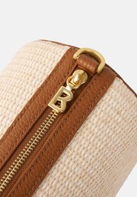 Woven natural fiber bag with brown leather accents and a gold zipper. Features a metal zipper pull with a "B" monogram.