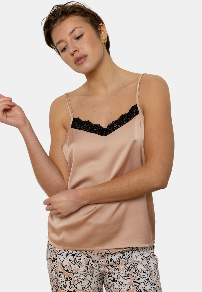 Camisole en satin de couleur beige doux avec une bordure en dentelle noire le long de l'encolure. Bretelles fines réglables et coupe lisse, légèrement ample.