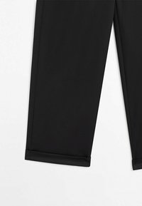 Pantalon noir ajusté avec une jambe étroite et un petit revers à l'ourlet, présenté sur un fond blanc.