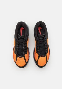 Černo-oranžové sportovní boty z síťovaného materiálu s texturovaným povrchem, šněrováním a červenými akcenty loga Nike.