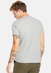 Grijze katoenen T-shirt met korte mouwen, ronde hals en een gladde textuur. Zichtbare tatoeages op de arm voegen detail toe.