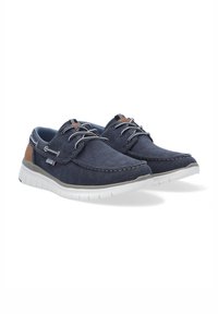 Marineblaue Segeltuchschuhe mit weißen Gummisohlen, mit braunen Lederelementen, Schnürung und genähten Kanten für Haltbarkeit.