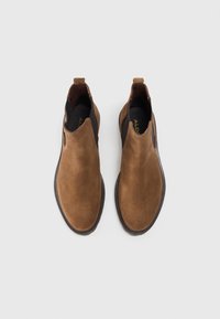Stivaletti Chelsea in suede marrone con pannelli elastici laterali, linguetta, punta tonda e suola in gomma, caratterizzati da una texture liscia e un design minimalista.