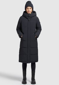 Abrigo de plumas negro con capucha, con cierre de cremallera, dos bolsillos frontales y un diseño largo y recto con secciones acolchadas.