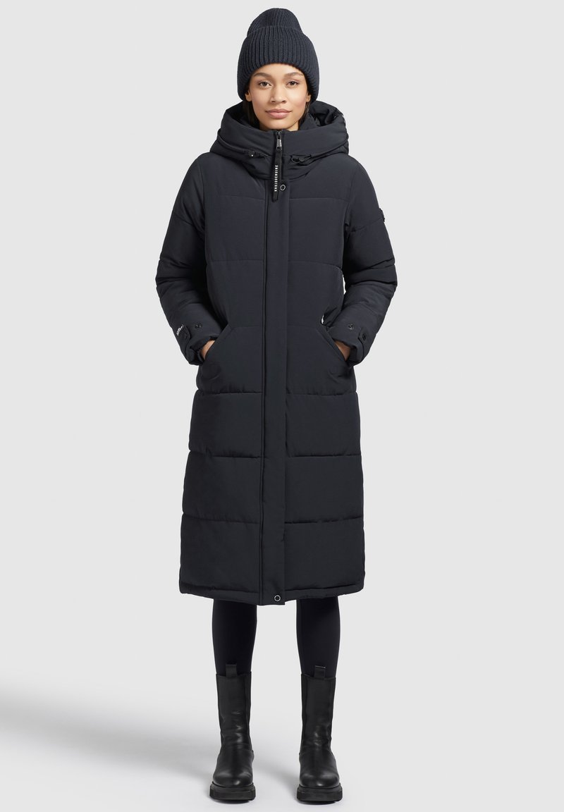 Abrigo de plumas negro con capucha, con cierre de cremallera, dos bolsillos frontales y un diseño largo y recto con secciones acolchadas.