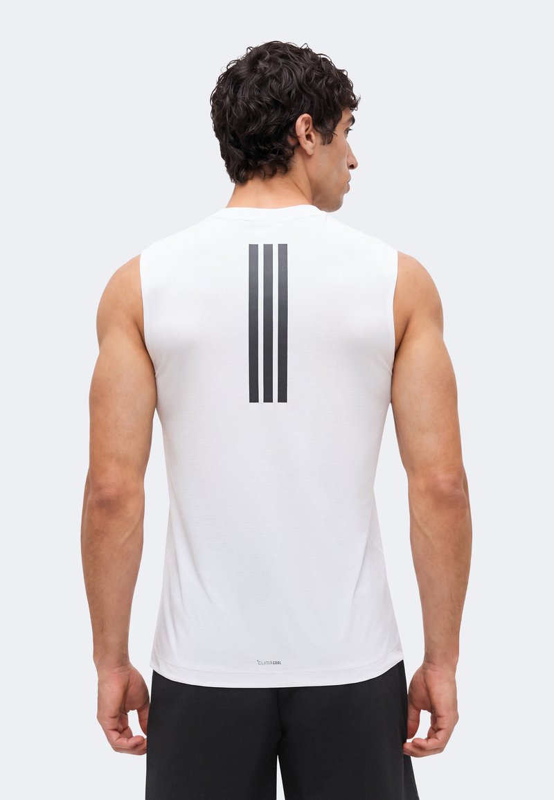 Man met zijn rug naar de kijker, gekleed in een wit mouwloos sportshirt met drie verticale zwarte strepen op de bovenrug en zwarte korte broek.