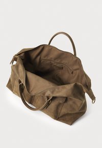 Sac de sport en daim marron avec une large ouverture, deux poignées supérieures et une poche zippée intérieure. Il présente des accessoires en métal doré et une texture douce.