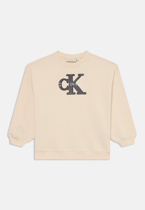 Béžová mikina s okrúhlym výstrihom a dlhými rukávmi. Na prednej strane sa nachádza čierne vyšívané logo "CK" a text "calvin klein".