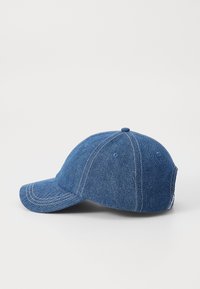 Gorra de béisbol de denim azul con visera curva, diseño de seis paneles, costuras blancas contrastantes y un botón en la parte superior.