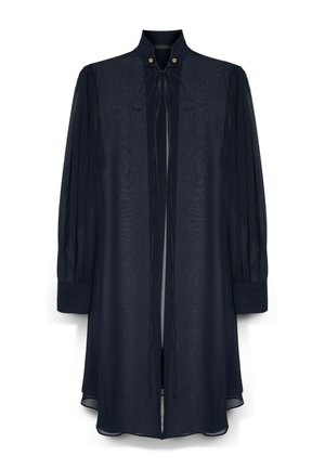 Donkerblauwe blouse met lange mouwen, hoge hals, striklinten aan de voorkant, geplooide mouwen en knoopdetails bij de halslijn.