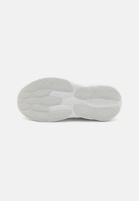 Semelle de baskets blanches présentant un motif de grip en caoutchouc texturé et des sections de nuances claires et sombres contrastées. Design plat et sportif.