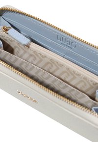 Portefeuille gris clair avec fermeture éclair dorée, présentant un intérieur bleu et un logo embossé. Contient plusieurs emplacements pour cartes et un compartiment zippé.