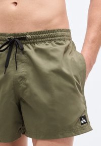 Πράσινα μαγιό σορτς από ελαφρύ ύφασμα, με ελαστική μέση και μαύρο κορδόνι, καθώς και πλαϊνές τσέπες. Λογότυπο στο τελείωμα.