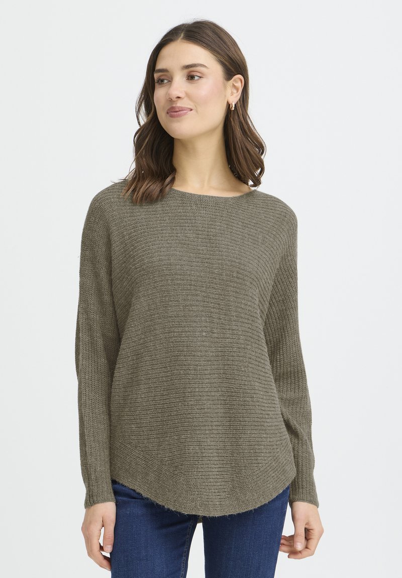 Pull en tricot vert olive à encolure ronde, manches longues, motif texturé et ourlet incurvé, associé à un jean bleu.