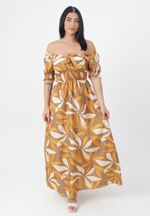 Robe maxi en marron et moutarde avec un motif floral. Design dénudé des épaules, taille smockée et manches courtes bouffantes. Le tissu semble doux et fluide.