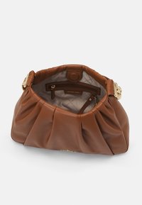 Borse in pelle marrone con accessori dorati, apertura superiore che mostra una tasca con zip interna e fodera beige con logo Michael Kors.