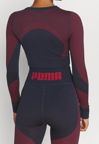 Marineblaues und burgunderfarbenes Sportset mit langen Ärmeln und hoch geschnittenen Leggings mit strukturiertem Design und "PUMA"-Logo an der Taille.