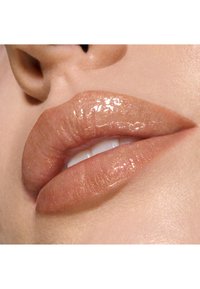 Couleur à lèvres nude brillante avec un subtil éclat, mettant en valeur des lèvres pulpeuses et lisses sur un fond de peau claire.