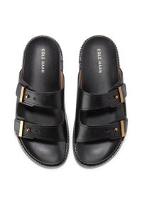 Svarta lädersandaler med tre remmar, guldiga detaljer och en slät yta. Etiketten säger "Cole Haan" på innersulan.