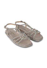 Sandalias planas beige con correas decorativas de plata, acabado de ante suave, diseño de punta abierta y cierre de hebilla en el tobillo para un ajuste seguro.
