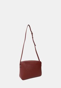 Borsa a tracolla rossa in pelle con design rettangolare strutturato, zip dorata e tracolla regolabile. Texture liscia, stile minimalista.