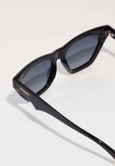 Óculos de sol pretos em plástico com lentes angulares, tonalidade em degradê cinza e logótipo dourado "Missoni" na lateral. Textura suave e design elegante.