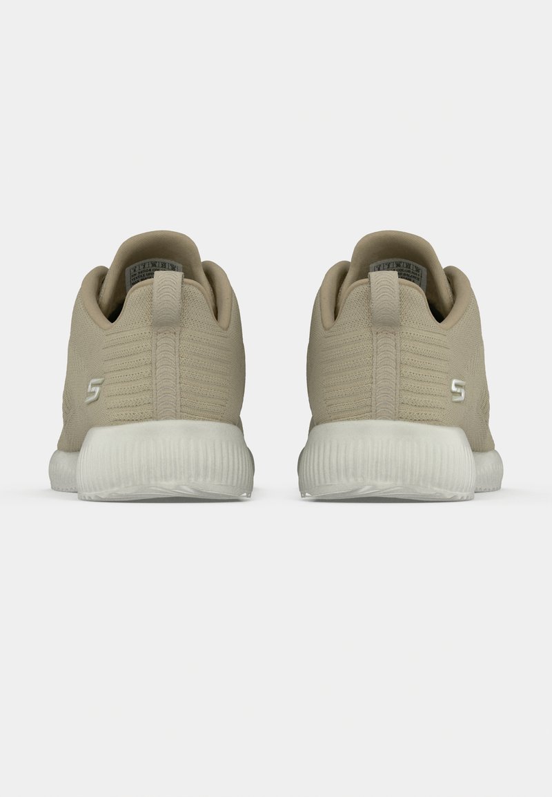 Zapatillas deportivas beige con parte superior de tela texturizada, tacón redondeado y suela de goma blanca. Presentan una mínima marca en el lateral.