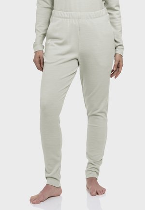 Person wearing off-white fitted sweatpants with elastic waistband, standing barefoot on a light surface.