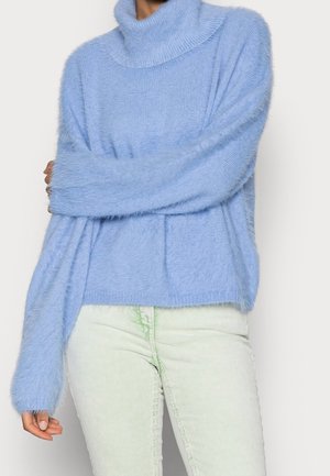Maglione fuzzy blu chiaro con collo alto, bordi a coste e maniche ampie, abbinato a pantaloni in velluto a coste verde chiaro.