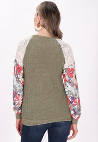 Olivenfarvet tætsiddende sweater med mønstrede blomsterærmer i rød og hvid, med en ribbet krop og rund halsudskæring.