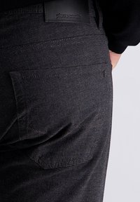 Donkere, gestructureerde broek met een subtiel patroon, voorzien van een achterzak en een zwart leren label met 'pierre cardin' in reliëf.