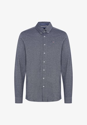 Chemise à manches longues boutonnée en tissu bleu marine. Présente un col classique, des boutons blancs et un petit logo avec des accents rouge, blanc et bleu.