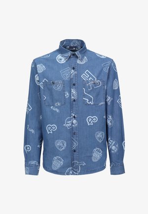 Camisa de mezclilla azul con logotipos y diseños de escudos impresos en blanco. Tiene un cierre de botones en la parte frontal, dos bolsillos en el pecho y mangas largas.